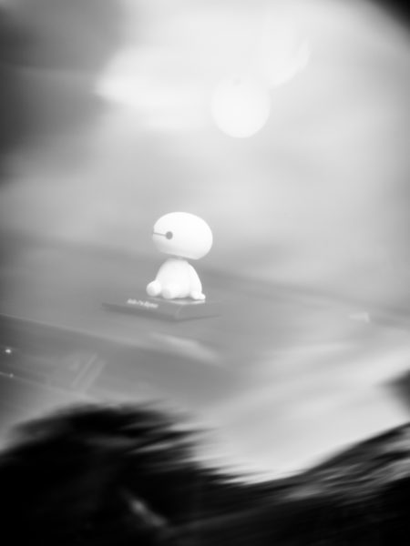 Baby alien toy sitting on a car dashboard fine art black and white photo