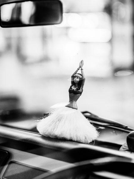 Hawaiian hula dancer toy with long grass skirt perched on a car dashboard