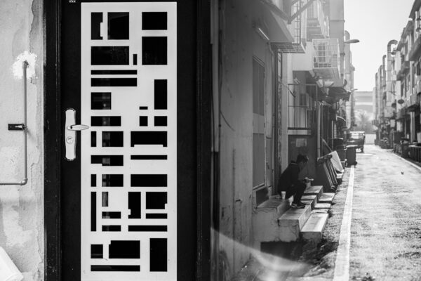 Black and white door grill frame and a young man taking a lunch break sitting on the stairs in TTDI Taman Tun Dr Ismail