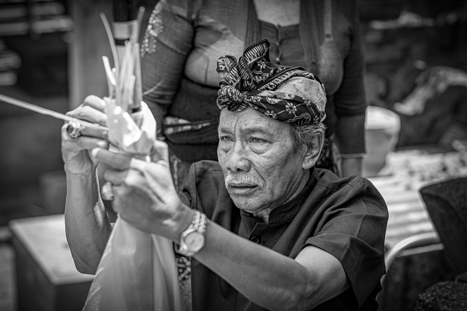 Ngaben cremation in Bali, the head of the family, and assistant to the priestess, is making the sandalwood effigy, which is then wrapped in a cloth and decorated.