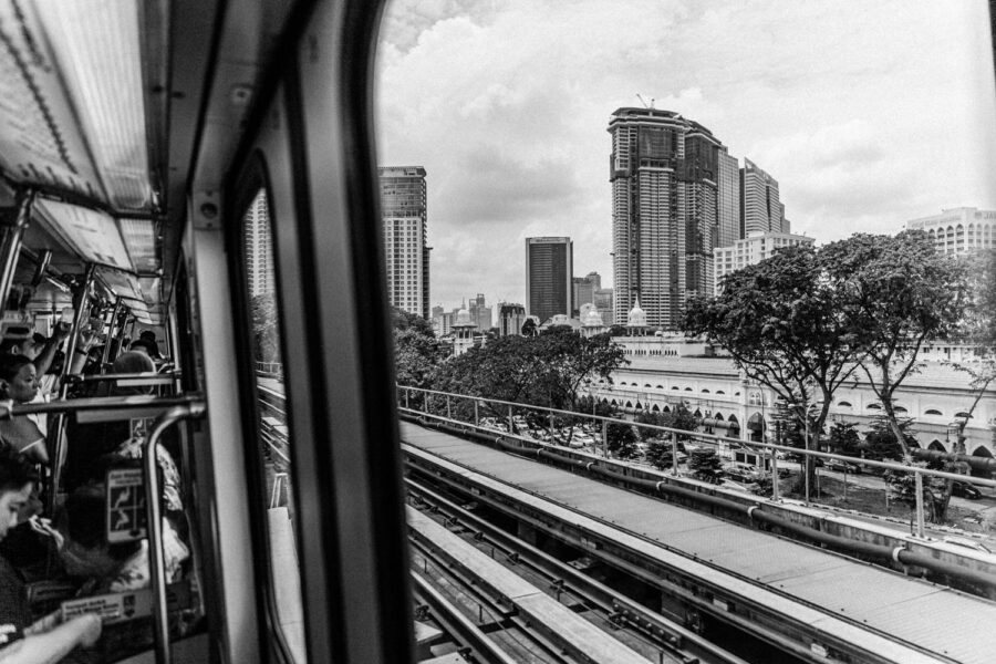 Rail skyscraper view and passengers aboard the LRT rail train traveling past Pasar Seni Chinatown in Kuala Lumpur