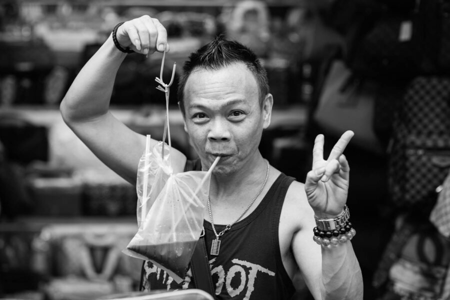 People photography a man in petaling street drinking from plastic bags