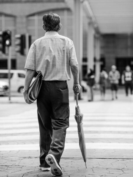 Man with an umbrella about to cross a pedestrian crossing Nu Sentral, Kuala Lumpur - Malaysia