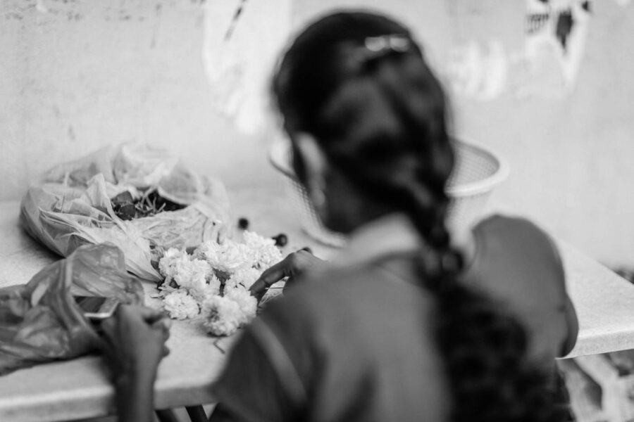 Women threading chrysanthemum flowers in Little India, Brickfields, Kuala Lumpur – Malaysia