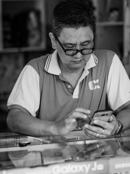 Man sitting in a shop using his mobile phone Pasar Seni, Kuala Lumpur – Malaysia