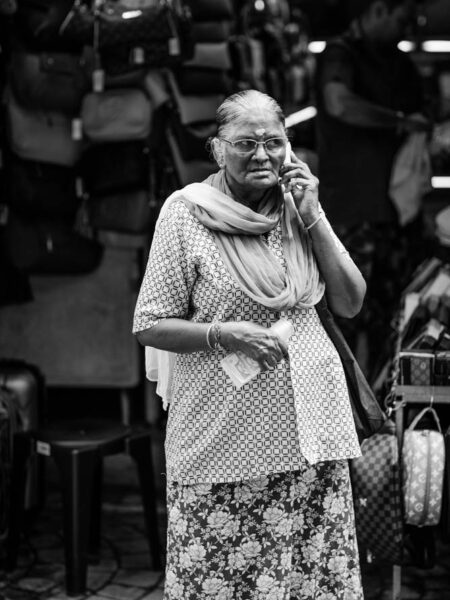 Woman on the phone, money notes in her hand, selling handbags in Petaling Street, Chinatown Kuala Lumpur - Malaysia