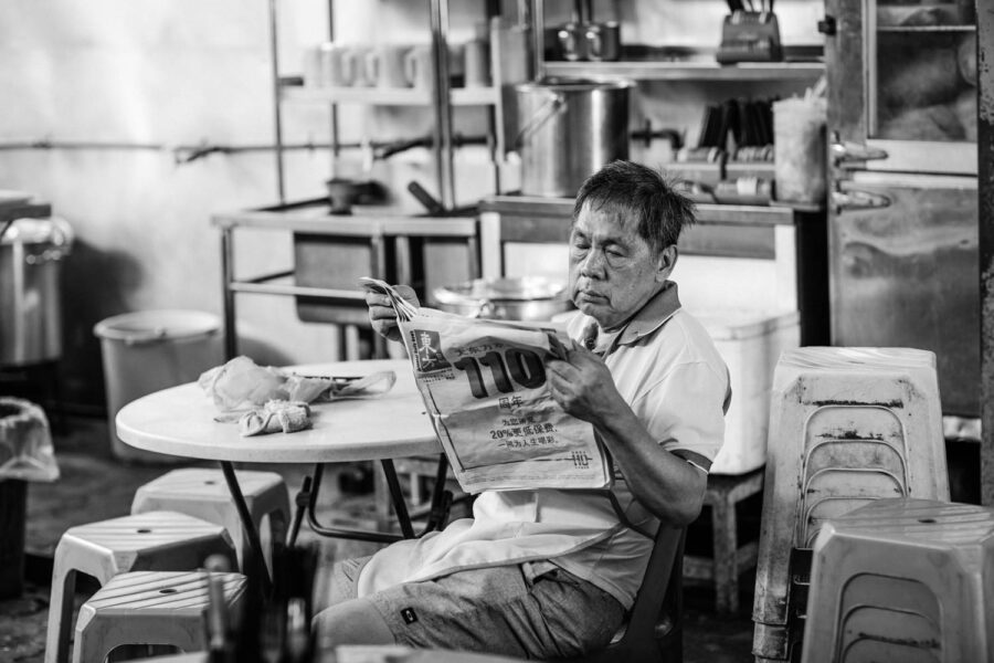 Man sitting reading a newspaper in a restaurant Pasar Seni, Kuala Lumpur – Malaysia