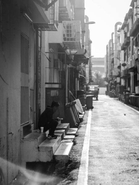 Man sitting on the stairs outside a restaurant having a break from work. Street photo TTDI.