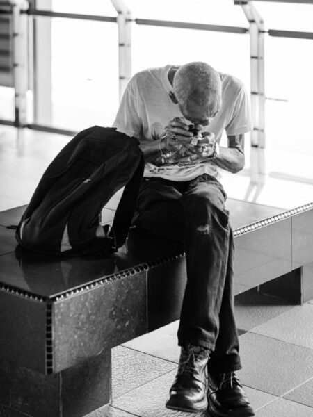 Man using an magnifying eye piece to magnify the details on a watch, while waiting for the next LRT train.