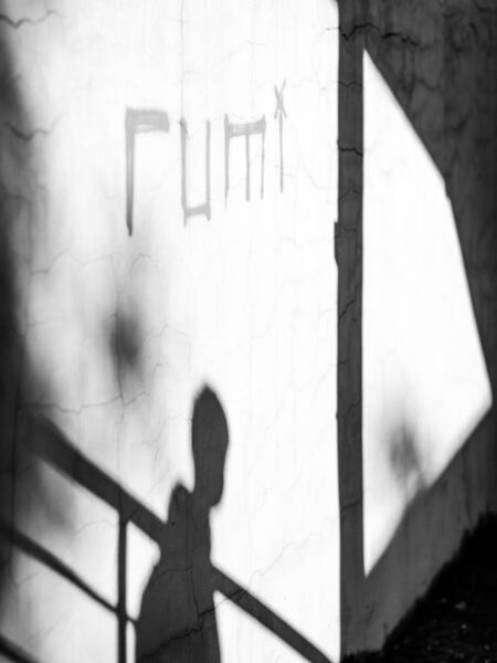 Tagging on a wall 'rumi' and a man's shadow as he walks down a flight of stairs. Street photo TTDI - KL