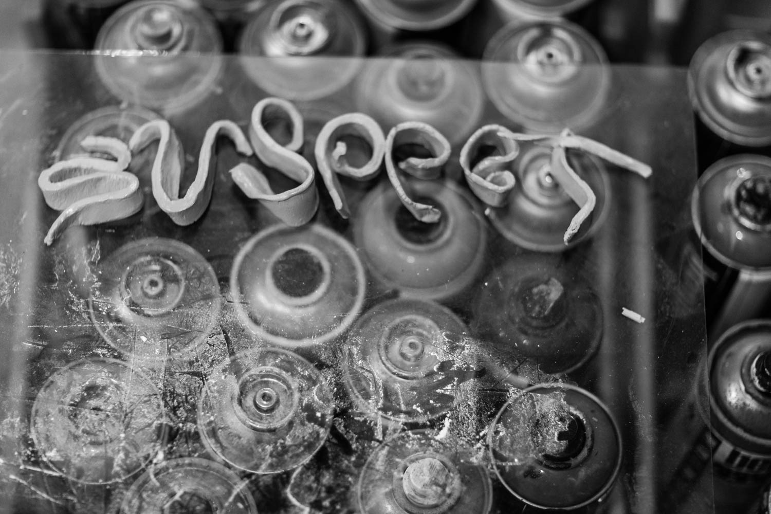 The word suspect on a makeshift table of paint spray cans.