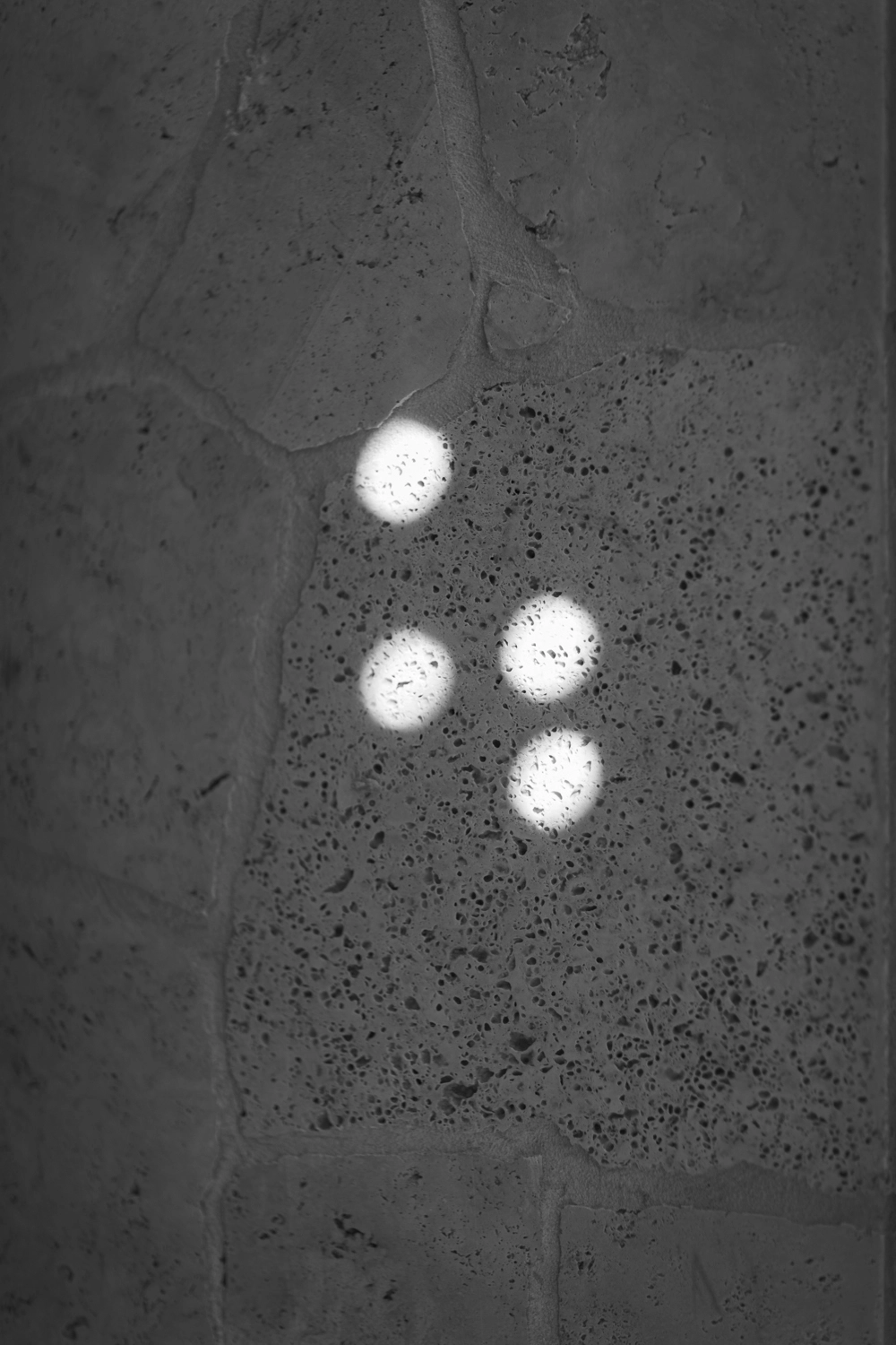 Four small circles of light shine on a stone footpath.