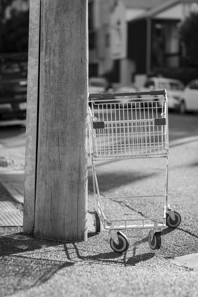A supermarket trolley was left beside a power pole.
