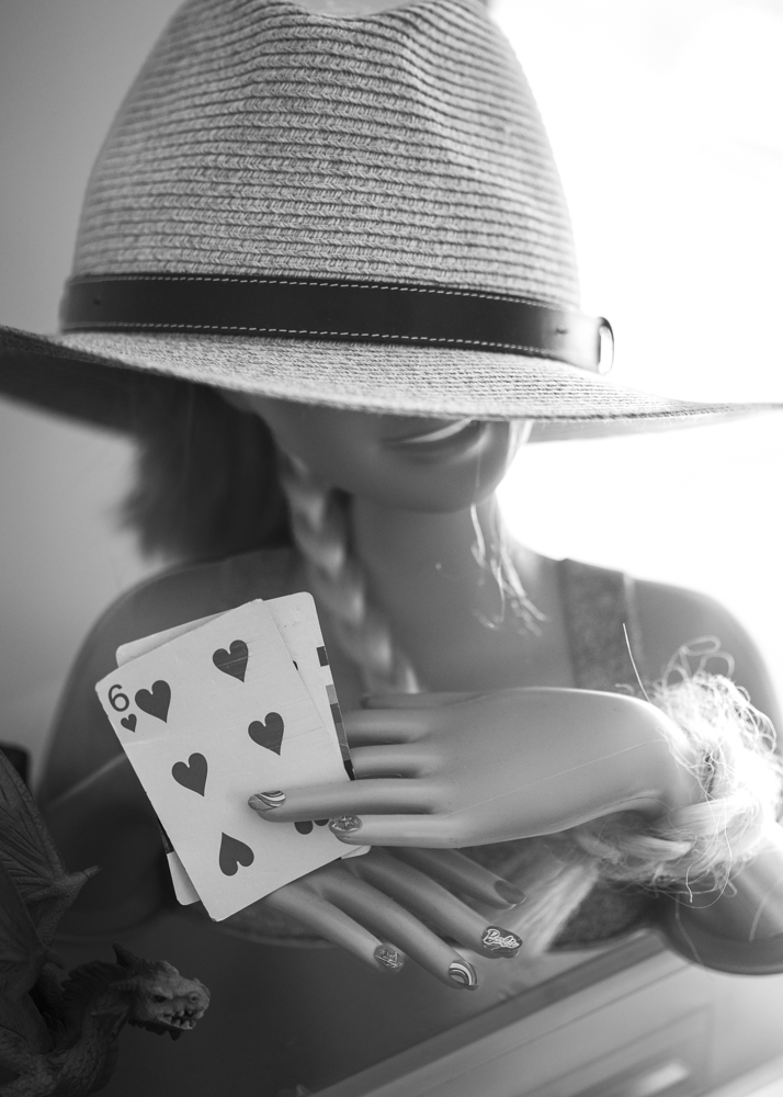 A mannequin holding a 6-heart playing card.