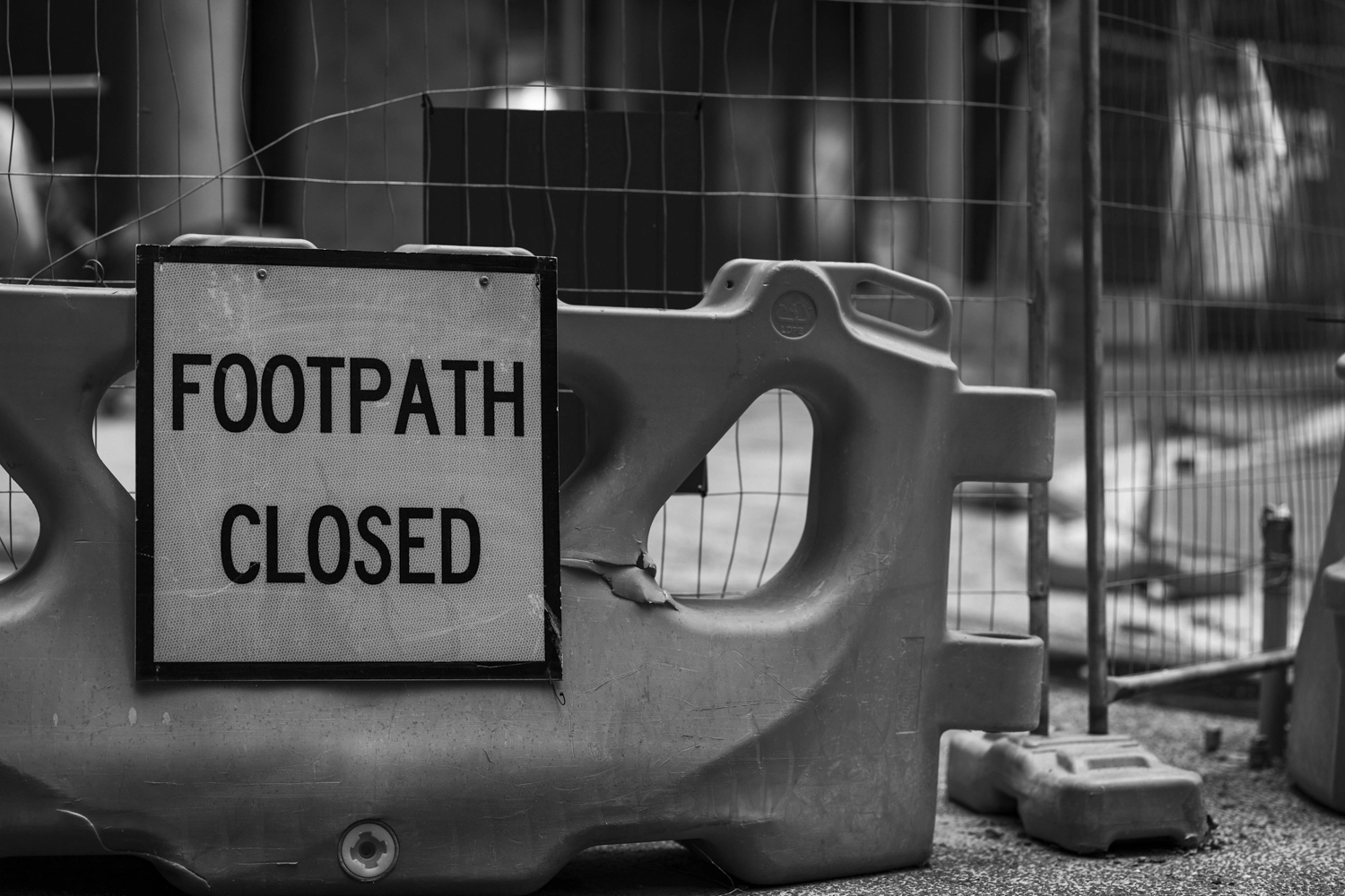 Footpath Closed sign on a large orange barrier block.