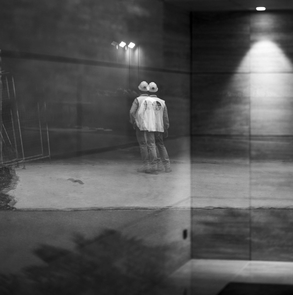 LIV Anura construction worker reflection inside the glass lobby of Luminare.