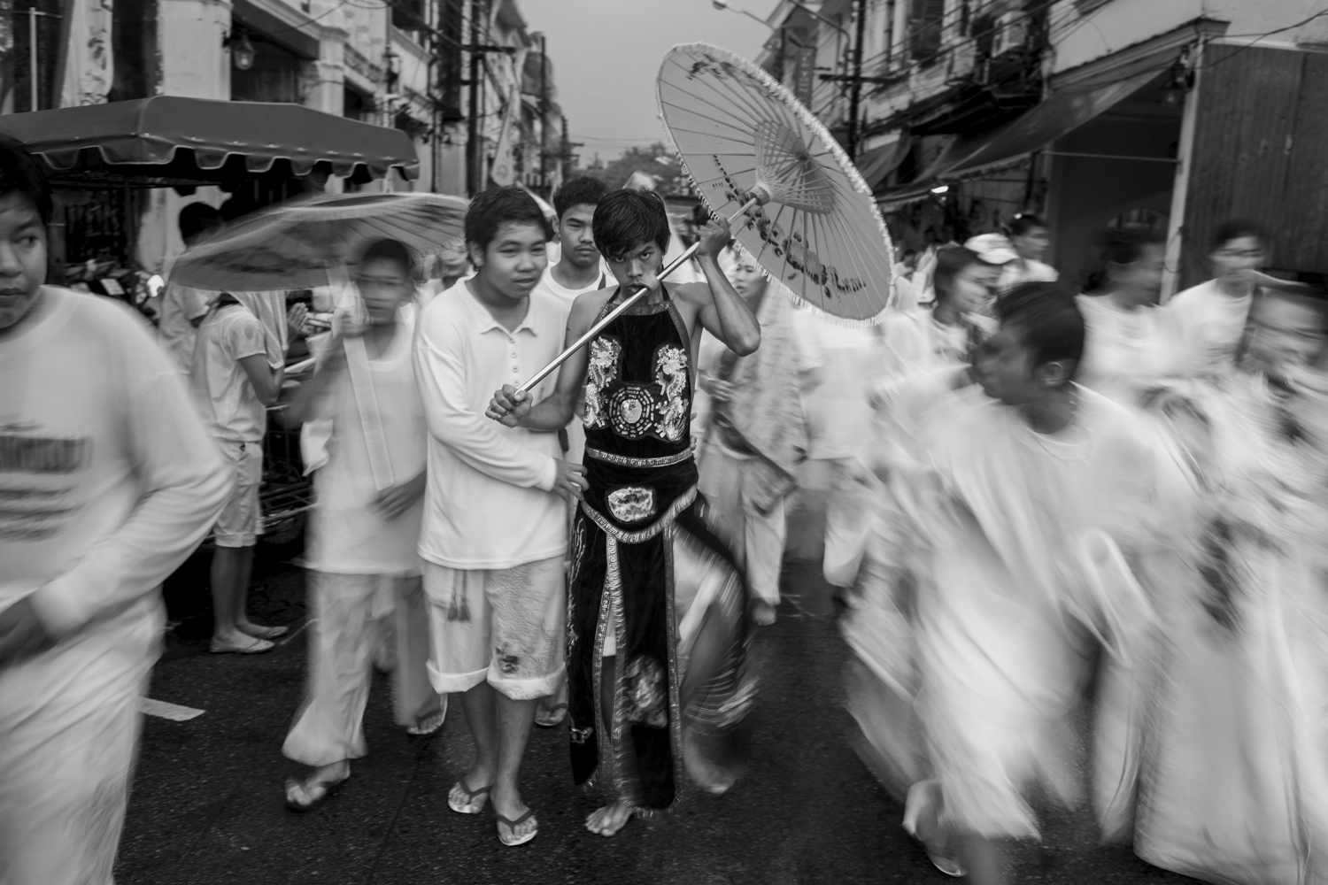 A spirit medium with a decorative umbrella piercing through this cheek at the Phuket Vegetarian Festival.