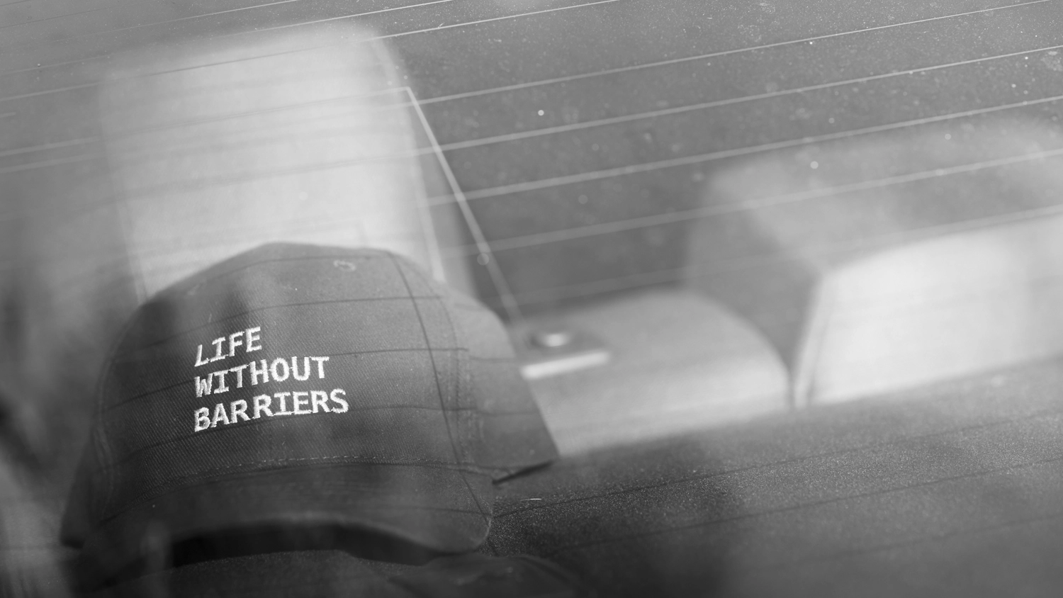 Cap with 'Life Without Barriers' text resting on a vehicle's dashboard.