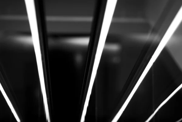 Abstract black and white photograph of bright linear reflections against a dark surface.